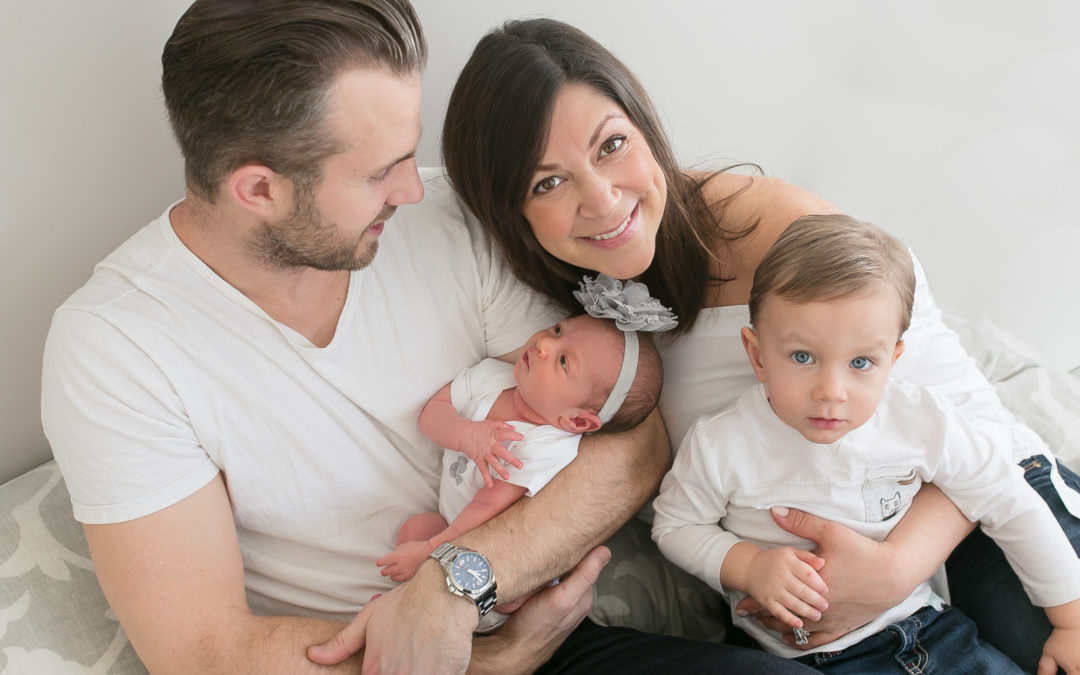 A family with a newborn and toddler on the bed, photographed by Paris Lenahan Photography.