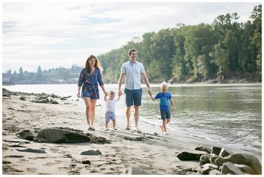 Family of four walk along a beach in New Westminster
